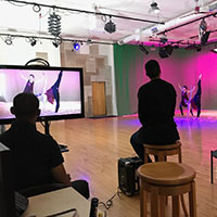 Dancers being video recorded and displayed on a monitor.