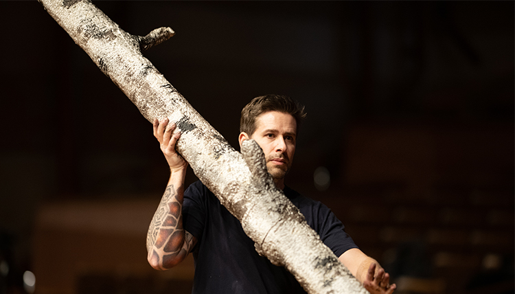 set technician Courtney Smith carries a tree trunk