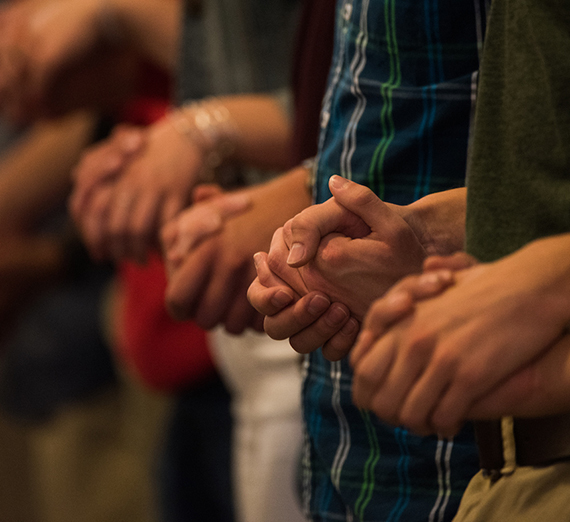 Community members hold hands in prayer for Mass of the Holy Spirit. 