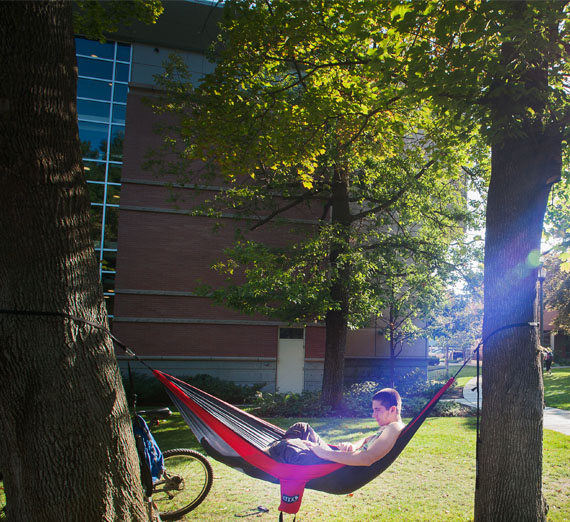 student laying in hammock on campus 