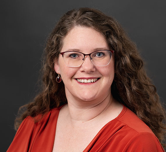 A woman in sunglasses claps in a crowd at a basketball game