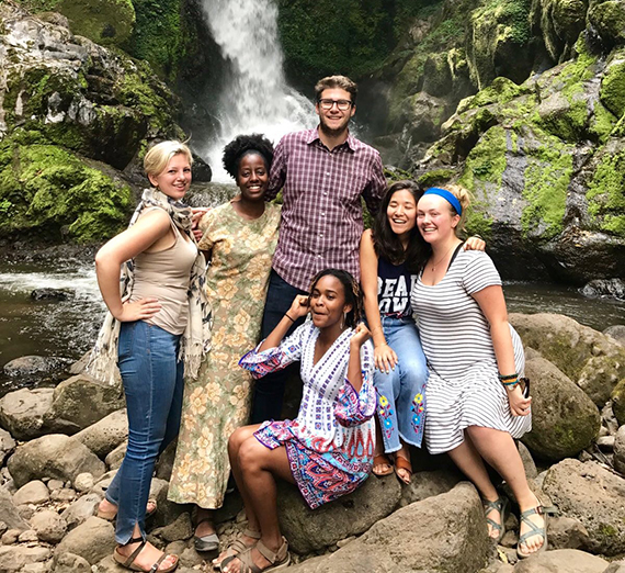 Aizley Hansen and her group in Tanzania sitting on rocks in front of a waterfall. 