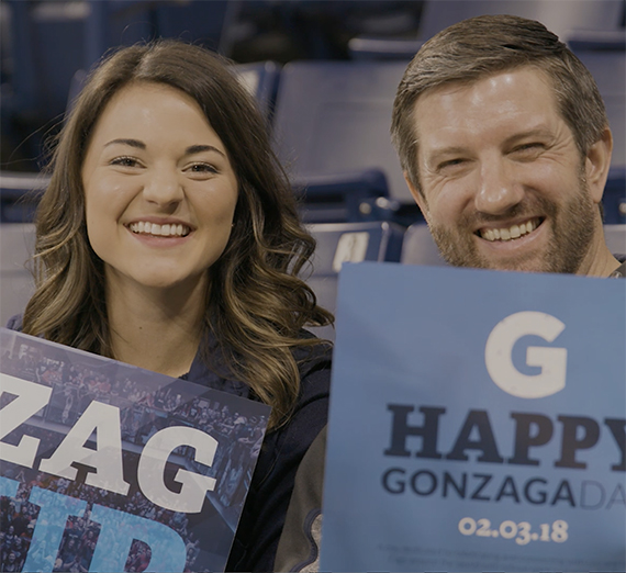 Gonzaga University students with their faces painted cheering in the Kennel Club student section at a basketball game