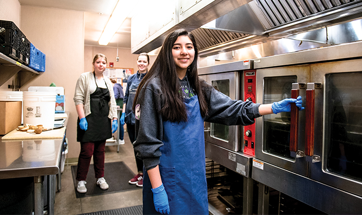 Students work to prepare food in the House of Charity kitchen. 