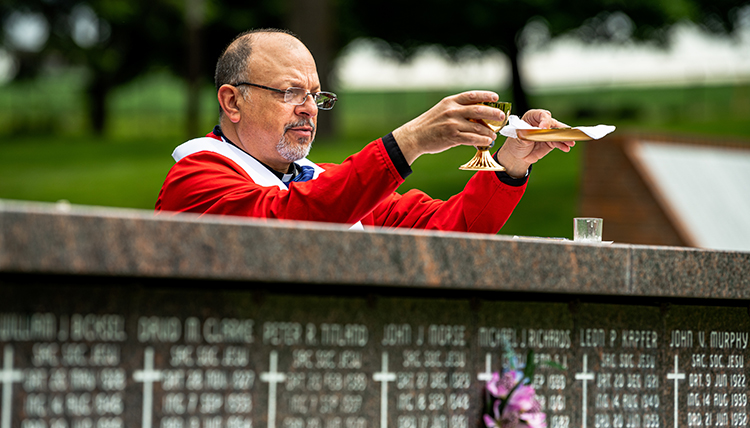 Jesuit priest offers communion to small gathering at cemetery