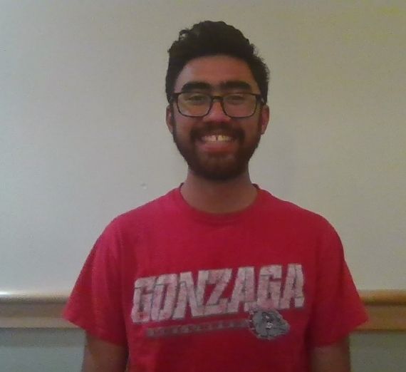 A photo of a current student. He is wearing a red shirt that says GONZAGA in white letters. He is smiling.