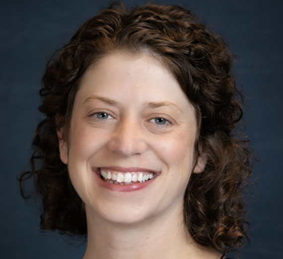 A main with a mustache wearing a brown t-shirt and necklace