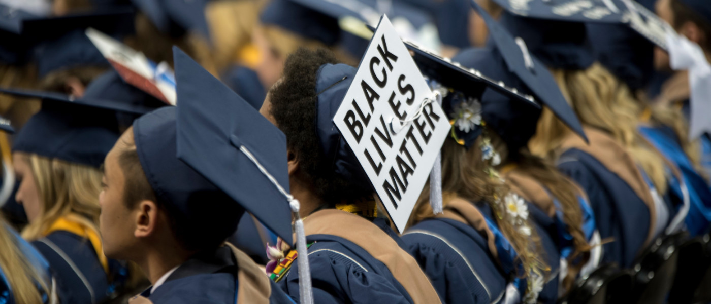 Student at commencement ceremony with a graduation cap that says 
