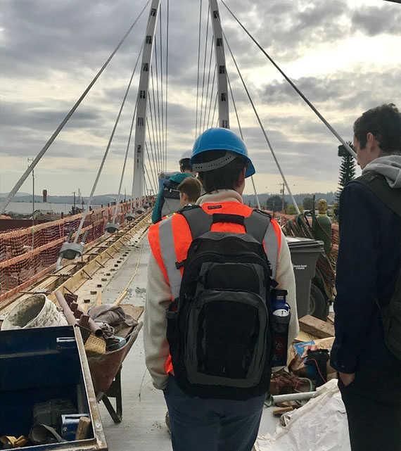 students in safety gear on a bridge construction site