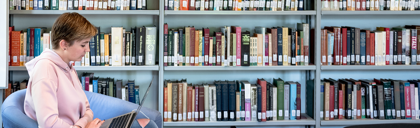 A student studies on her laptop in the library