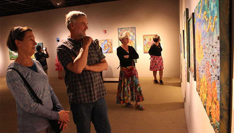 A man and a woman gaze at a painting in a gallery in a museum. A man and a woman gaze at a painting in a gallery in a museum.