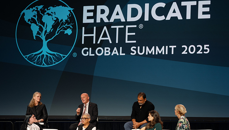 A group sitting in front of a sign saying Eradicate Hate Global Summit 2025
