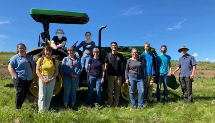 Students and faculty grouped with a tractor in a field.