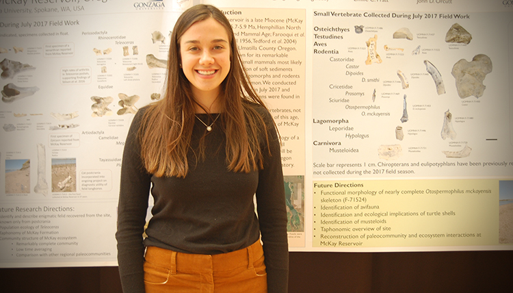 A student proudly stands in front of her research project board. A student proudly stands in front of her research project board.
