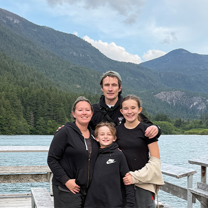 TJ and his family on a lake with mountains in the background 