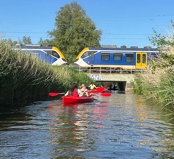 Two kyacks with students row under a train crossing the trestle