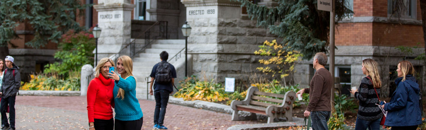 student and parent take picture in front of College Hall 