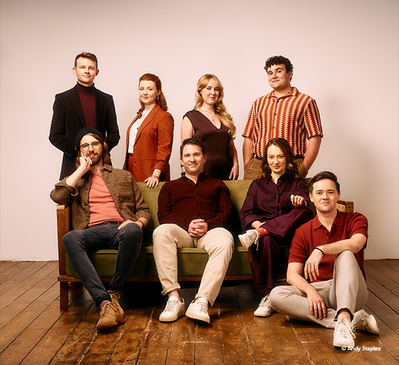 VOCES8 posed on and around a couch. 