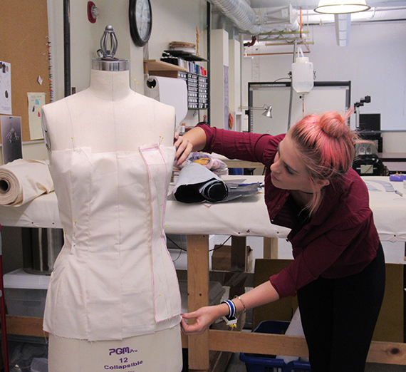 student measuring a garment she made 