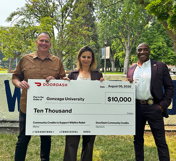 three individuals hold oversized check made out for $10,000