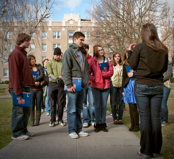 Students on a campus tour with Desmet hall in the background.