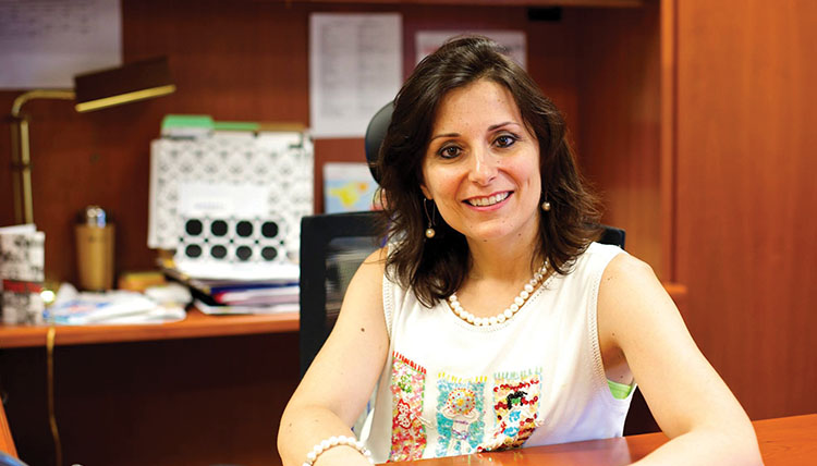 President Passerini smiling with her arms rested on a desk President Passerini smiling with her arms rested on a desk