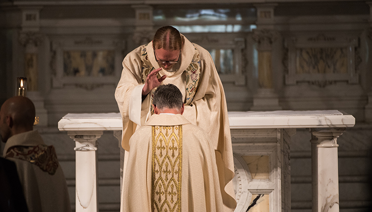 One Jesuit priest prays over a new Jesuit priest in ceremony at St. Aloysius One Jesuit priest prays over a new Jesuit priest in ceremony at St. Aloysius