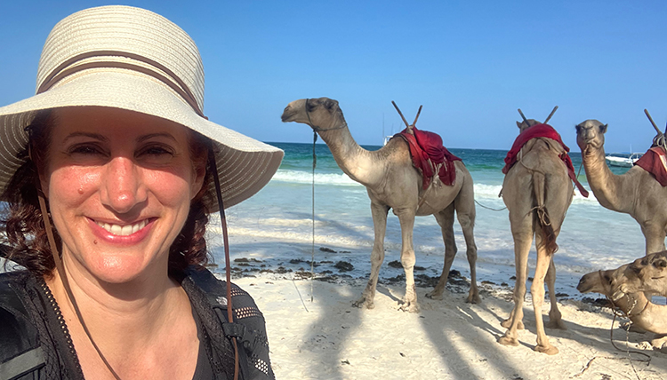 Professor Juliane Mora standing in front of camels