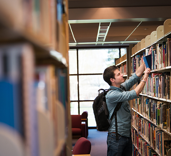 student grabbing books from shelf