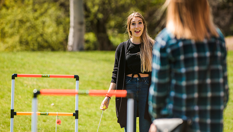 Female students playing a game of ladder toss in a field Female students playing a game of ladder toss in a field