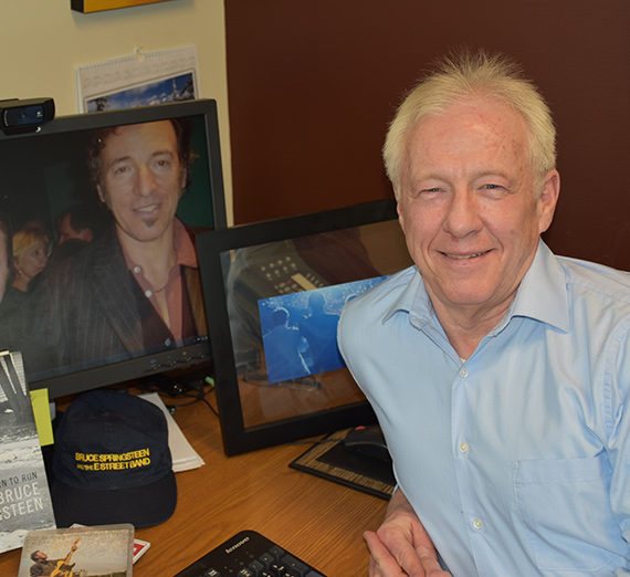 Albert Greely poses with his computer monitor, showing a Bruce Springsteen wallpaper