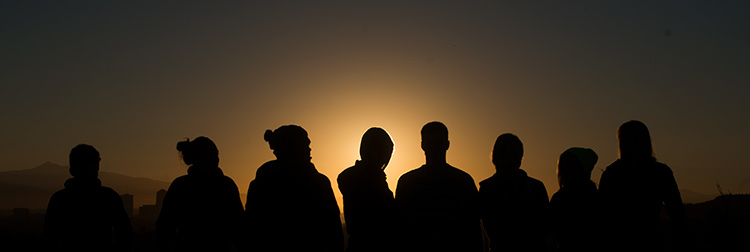 A group of students are silhouetted against the sunset A group of students are silhouetted against the sunset