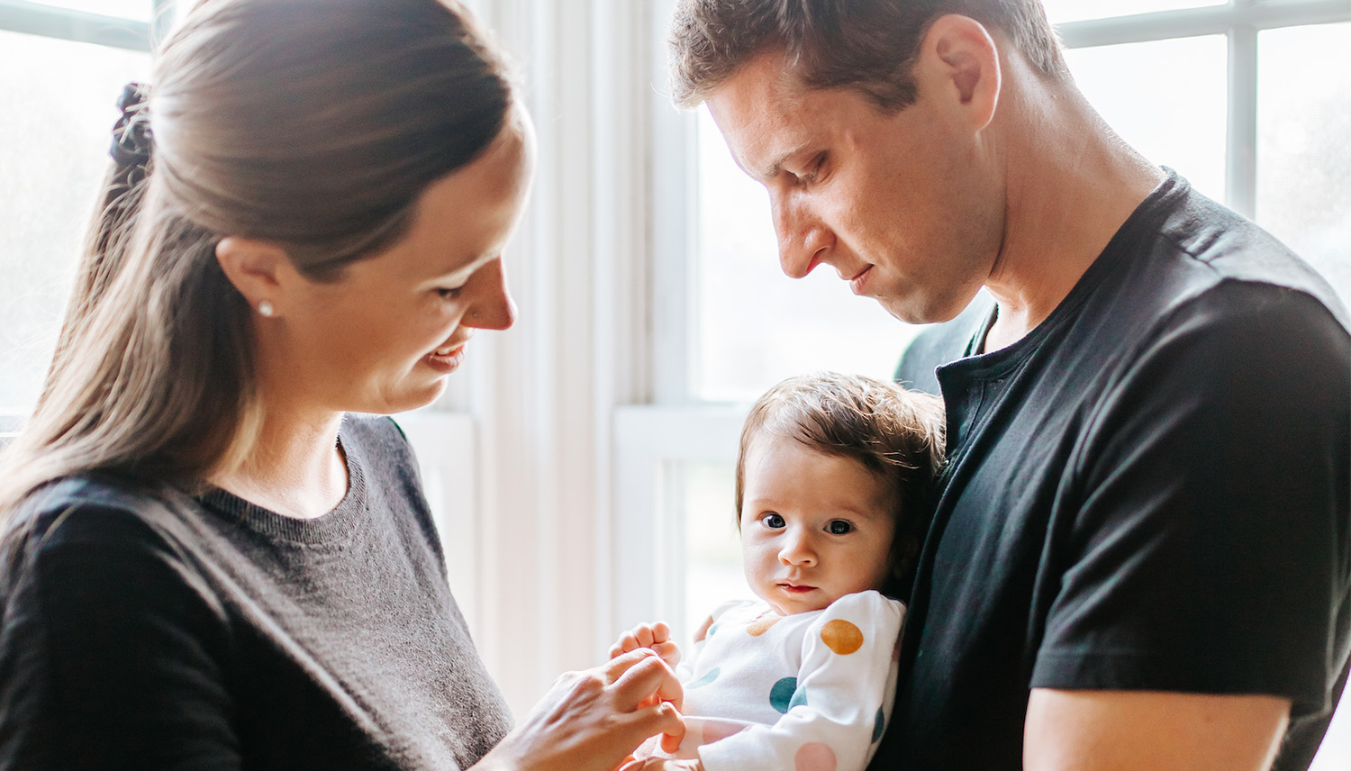 Two parents hold their baby Two parents hold their baby