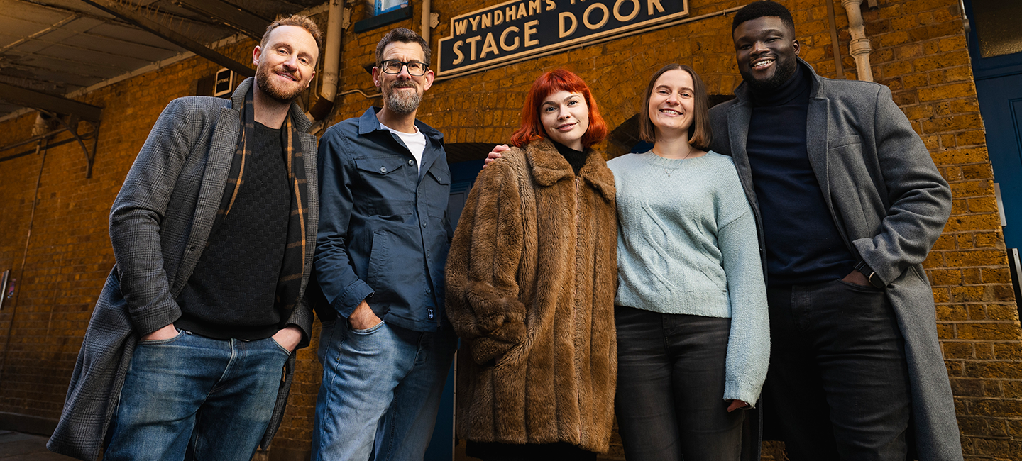 Five actors posed in a line in front of the Wyndam's Theatre Stage Door.