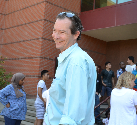 Dr. James Hunter stands in front of a group of kids who are posing for a group photo.