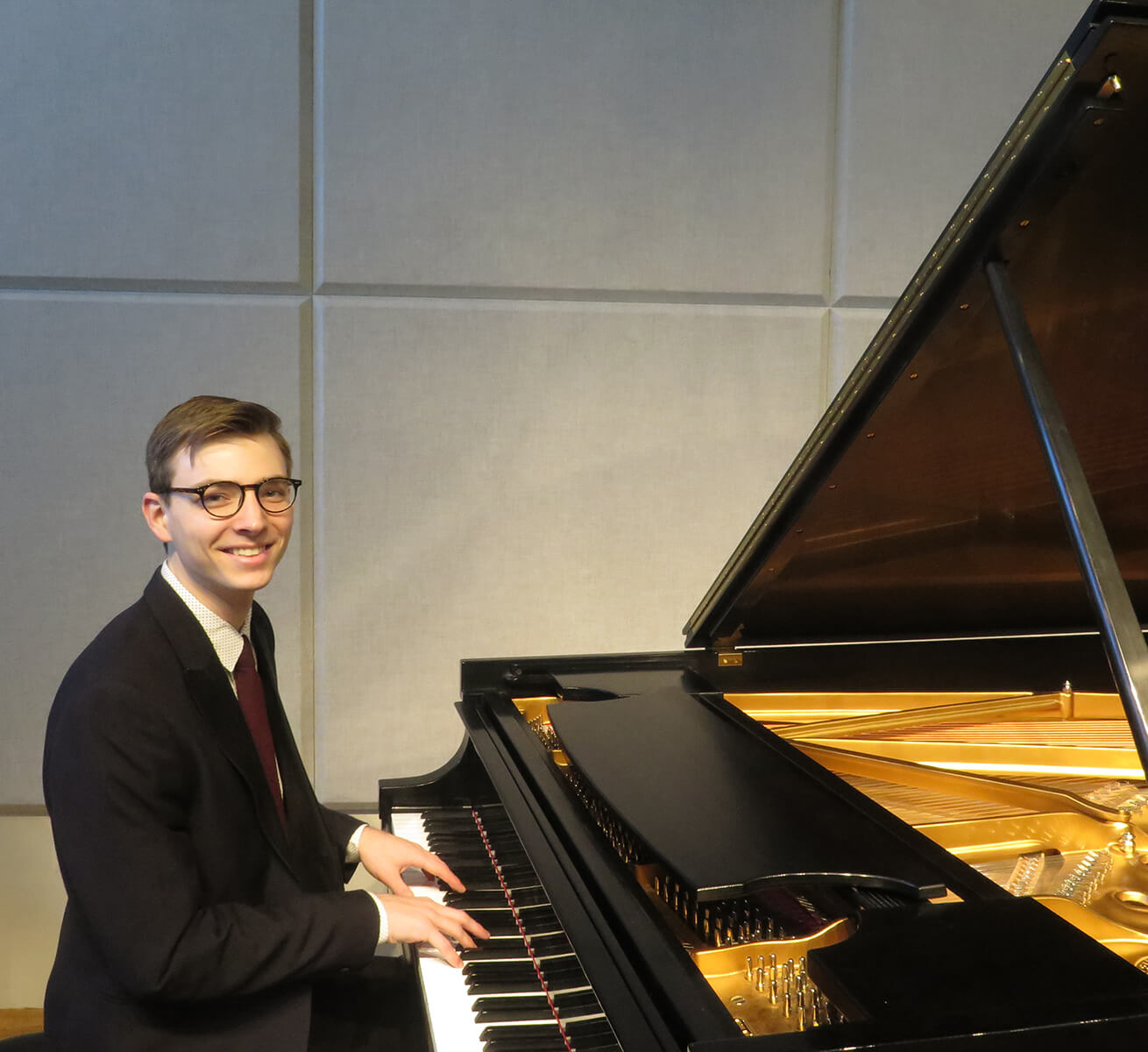 Picture of a student in a suit playing the piano