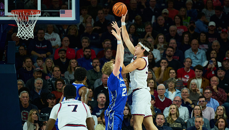A man shoots a ball over a defender in basketball