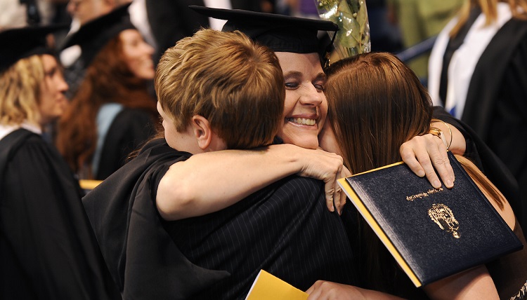 A graduate embraces her children after receiving her degree during the Graduate Commencement ceremony. A graduate embraces her children after receiving her degree during the Graduate Commencement ceremony.