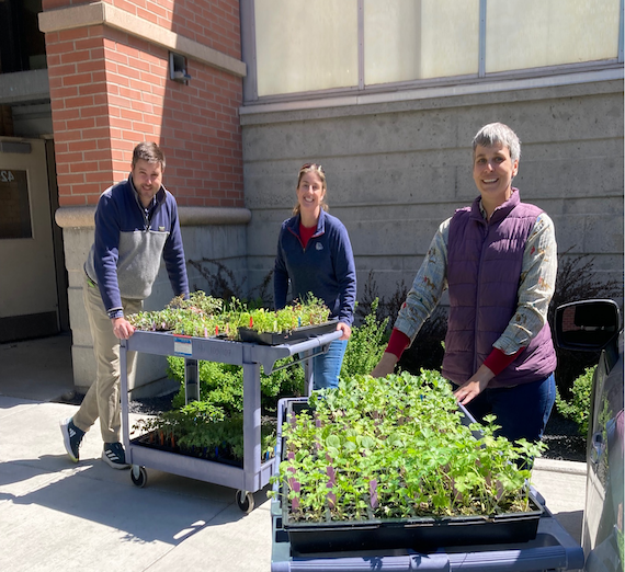 GU staff members Brian, Rebekah, and Abbey stand in front of trays of many plant starts, ready to be delivered to resource organization Our Place. GU staff members Brian, Rebekah, and Abbey stand in front of trays of many plant starts, ready to be delivered to resource organization Our Place.