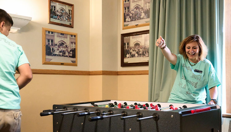 President Passerini smiling while playing foosball with a student President Passerini smiling while playing foosball with a student