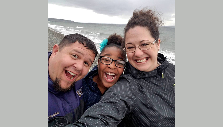 happy parents with adopted older child on the beach happy parents with adopted older child on the beach