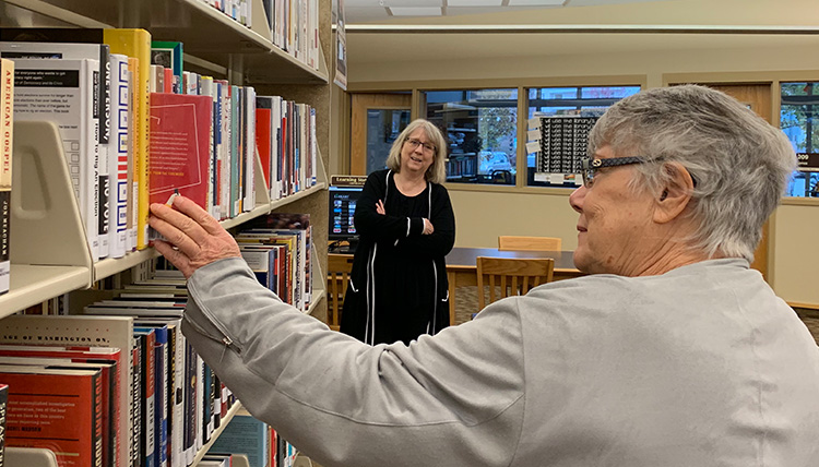 woman pulls book from shelf at library woman pulls book from shelf at library