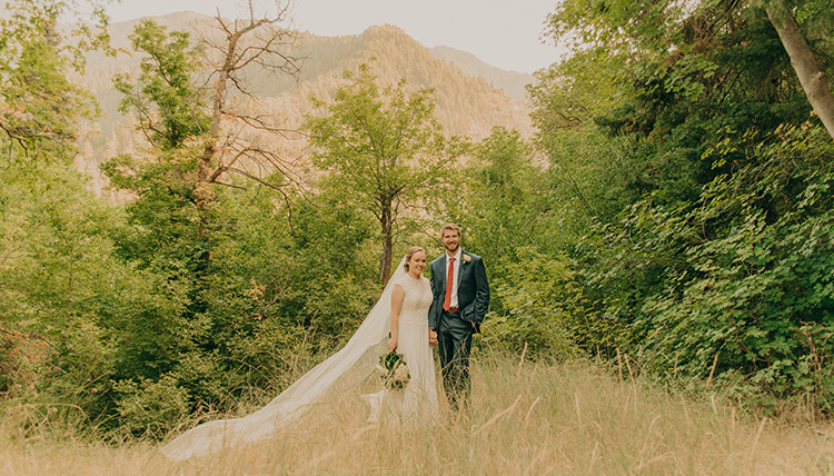 Man and women pose in a field with a long veil. Man and women pose in a field with a long veil.