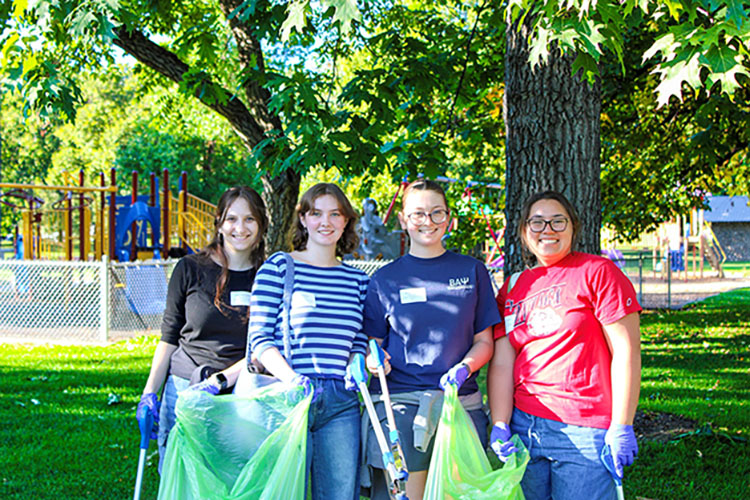 Four people holding trash bags.