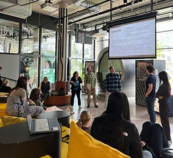 Classroom setting with a teacher gesturing to a projection screen