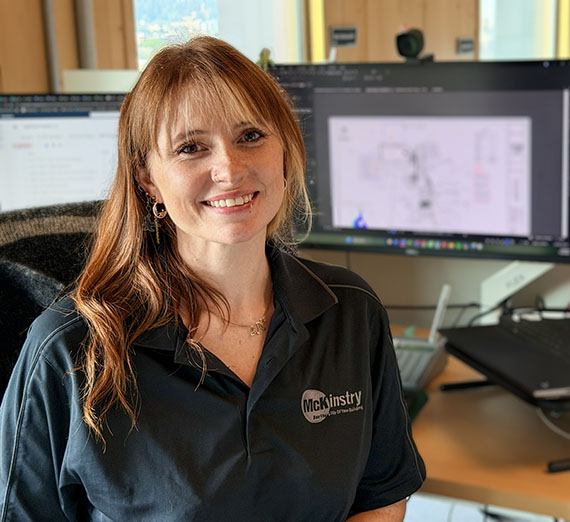 Woman wearing a shirt with the word McKinstry sits at a desk with computer screens