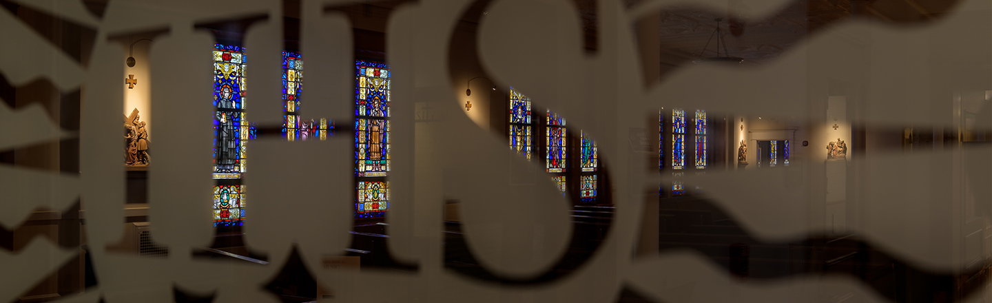 Decorative image looking through a glass door towards stained glass in a church.