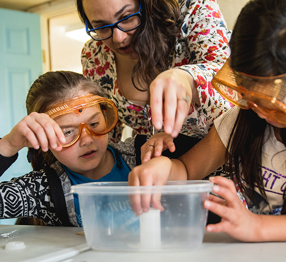 Two youth conduct an experiment with their instructor. Two youth conduct an experiment with their instructor.