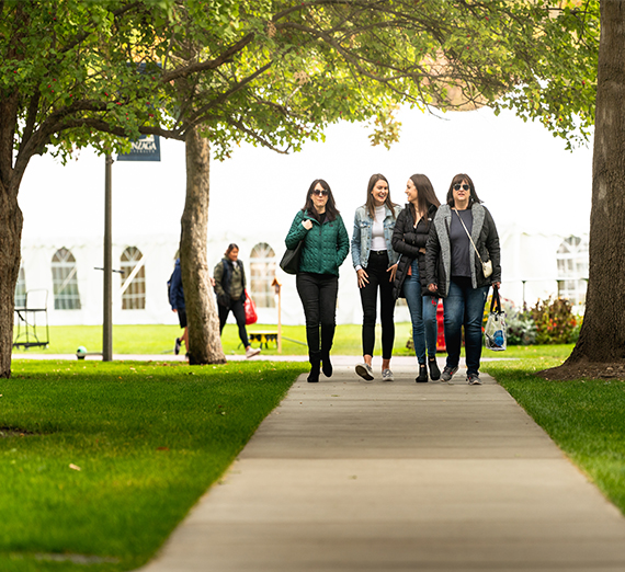 A group of visitors walk down a sidewalk while exploring campus.