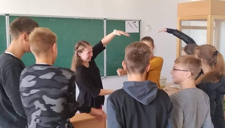 Woman in a classroom smiling as she works with a group of students Woman in a classroom smiling as she works with a group of students